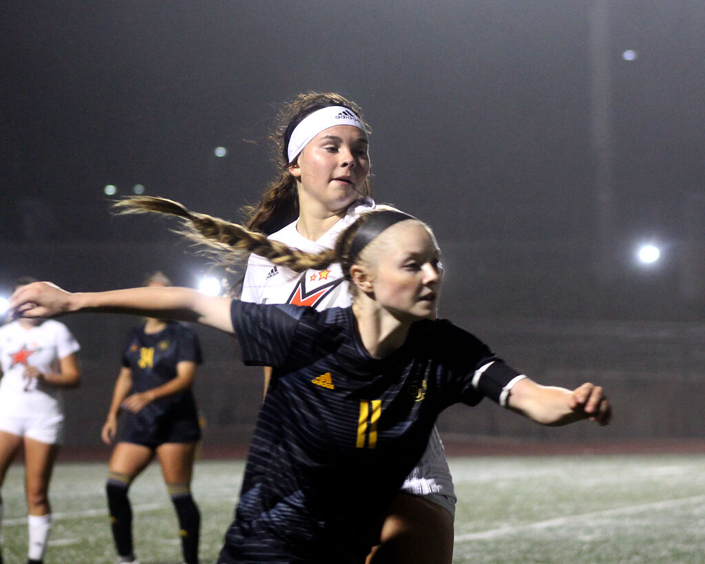 Sophomore Peyton Lane looks over Ottawa's Denaya Evans' shoulder to see where her teammate is kicking